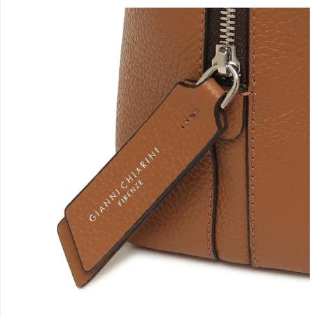 Primer pla de la bossa de pell marró de GIANNI CHIARINI. Té una cremallera metàl·lica i una etiqueta de cuir que diu "GIANNI CHIARINI FIRENZE" en blanc. Està fabricat a Itàlia i desprèn una elegància italiana atemporal.