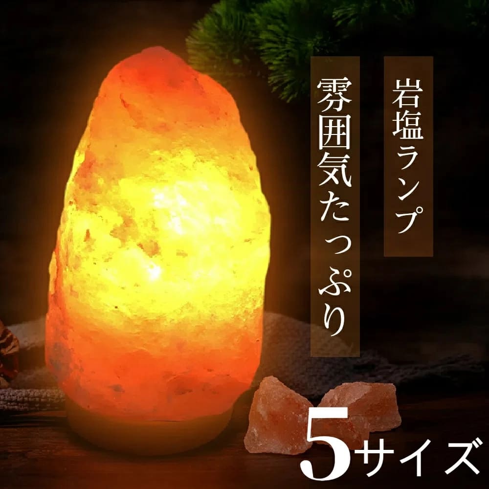 オレンジ色に輝く天然岩塩ランプ【サイズ：SS】— ほっと落ち着く、優しい間接照明が、暗い台座の上に置かれており、その横には日本語の文字と2つの岩塩が添えられている。ランプからは、温かみのある間接照明が放たれている。下部には白文字で「5サイズから選べます」と書かれている。.